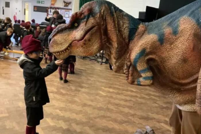 A kid petting Jam the T-Rex